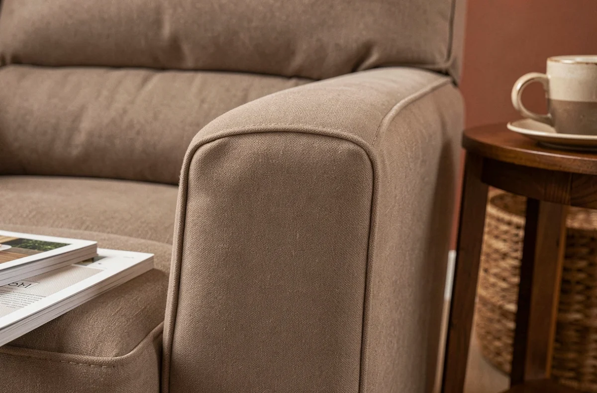 Gros plan sur la texture d'une housse extensible taupe ajustée sur l'accoudoir et le coussin d'un fauteuil relax